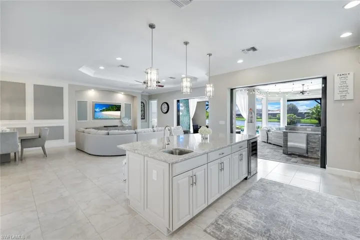 Kitchen featuring with  white cabinetry, a kitchen island with quartz countertop and sink