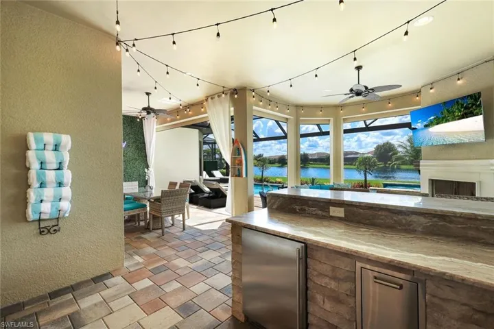 View of patio with ceiling fan, area for grilling, a bar, and a water view