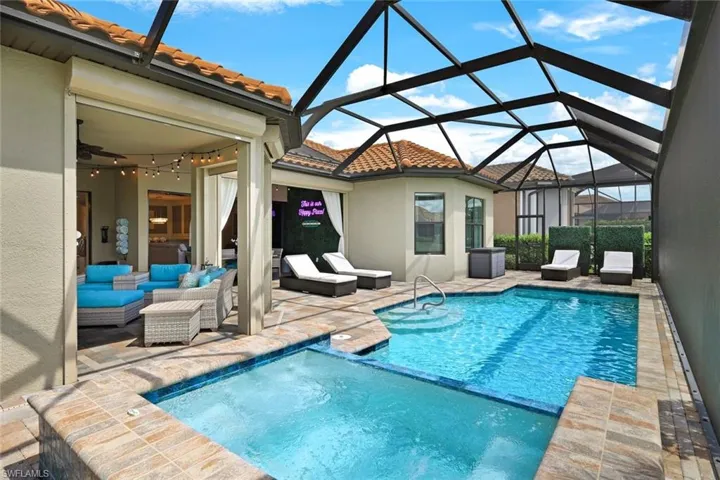 View of swimming pool and spa featuring screen enclosure, outdoor lounge area, and a patio area