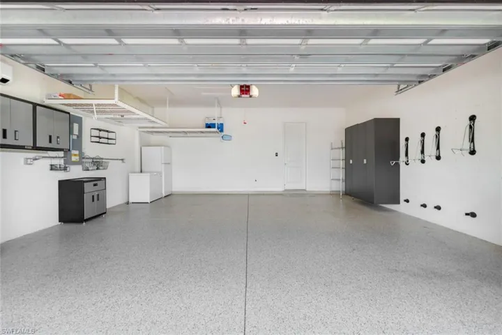 Garage with a garage door opener and white fridge and freezer