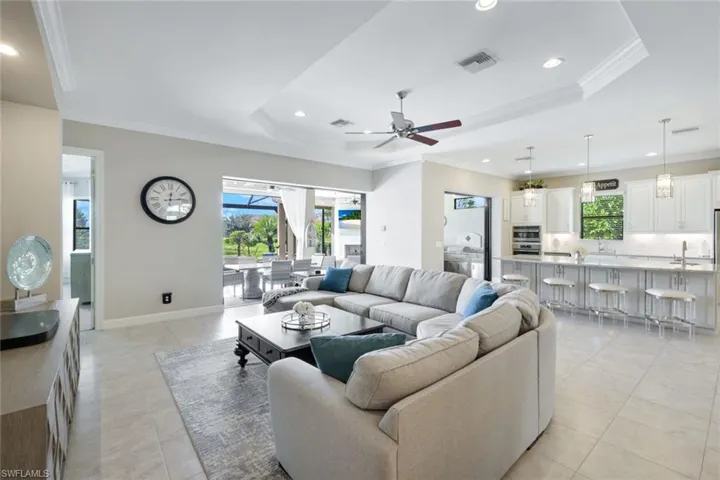 Living room featuring ceiling fan, a tray ceiling, and crown molding