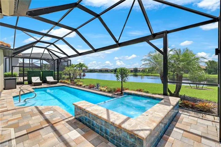 View of swimming pool featuring a patio, a water view, an in ground hot tub, and screen enclosure