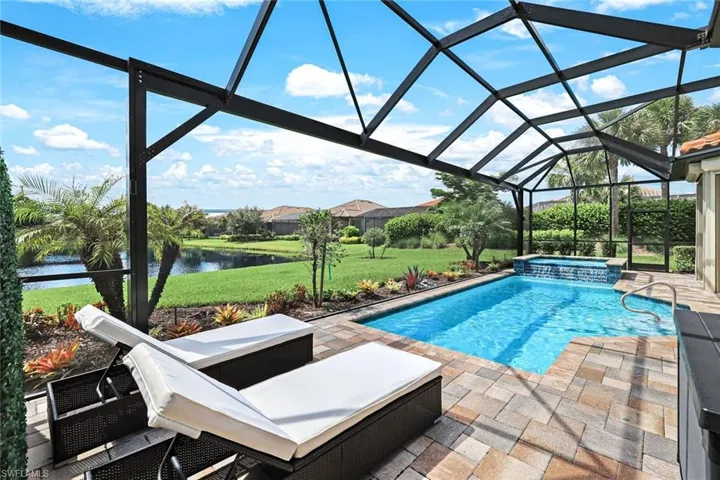 View of pool featuring a patio, a water view, a yard, an in ground hot tub, and a lanai