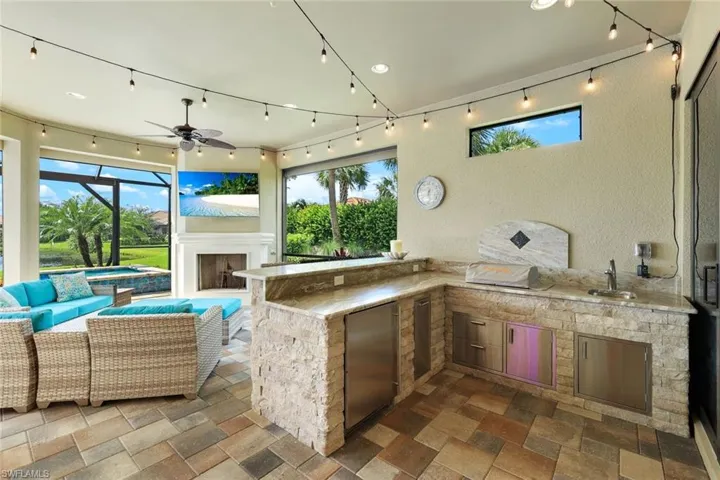 View of patio with outdoor kitchen, grill, fridge