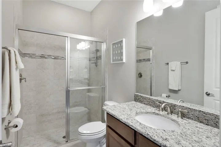Bathroom with an enclosed shower, vanity, and toilet