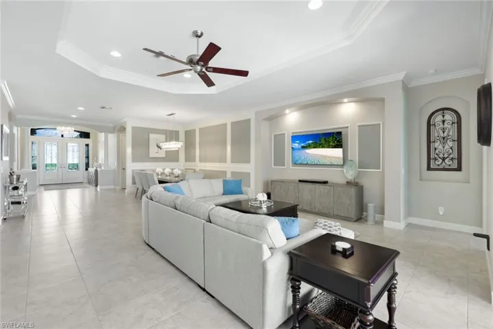 Living room with ceiling fan, crown molding, and TV niche