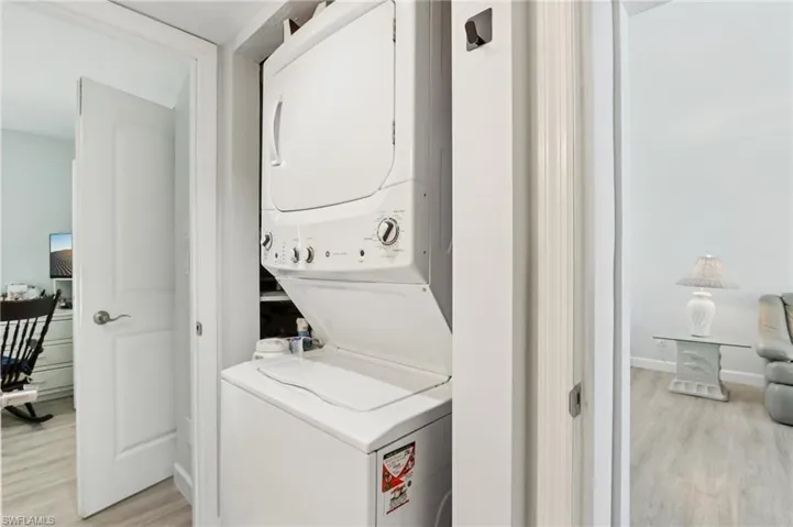 Laundry area featuring light wood-style flooring and stacked washing machine and dryer
