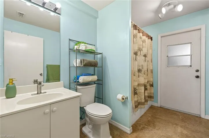 Full bathroom with visible vents, a shower with curtain, toilet, baseboards, and vanity.  Access to screened lanai so it can be a future pool bathroom!