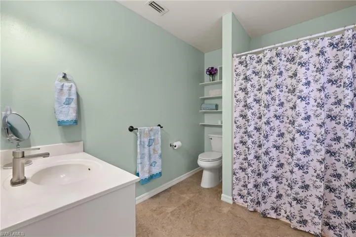 Full bathroom with visible vents, curtained shower, baseboards, toilet, and vanity