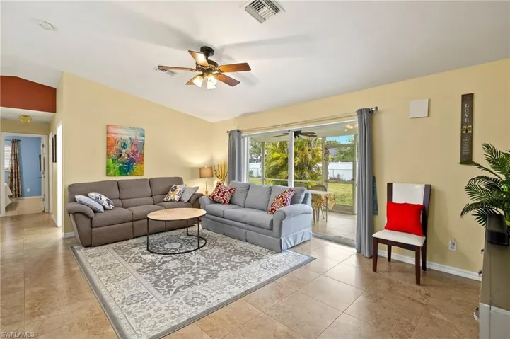 Living area with a ceiling fan, visible vents, baseboards, lofted ceiling, and light tile patterned flooring