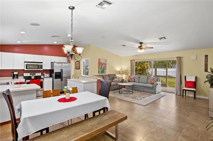Dining room featuring vaulted ceiling, light tile patterned floors, baseboards, and visible vents