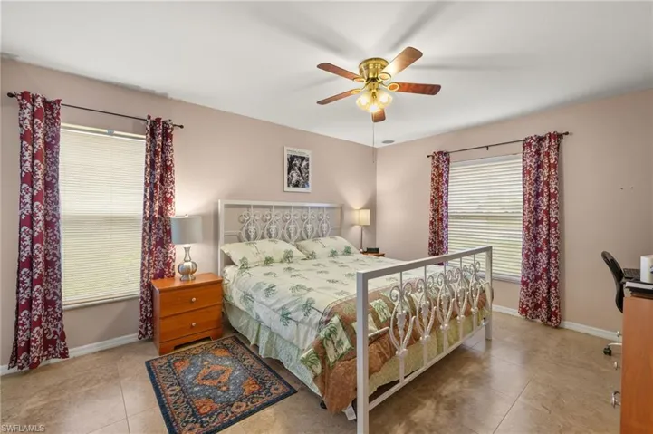 Tiled bedroom with baseboards and ceiling fan