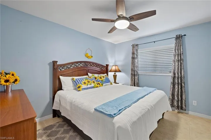 Bedroom featuring tile patterned floors, ceiling fan, and baseboards