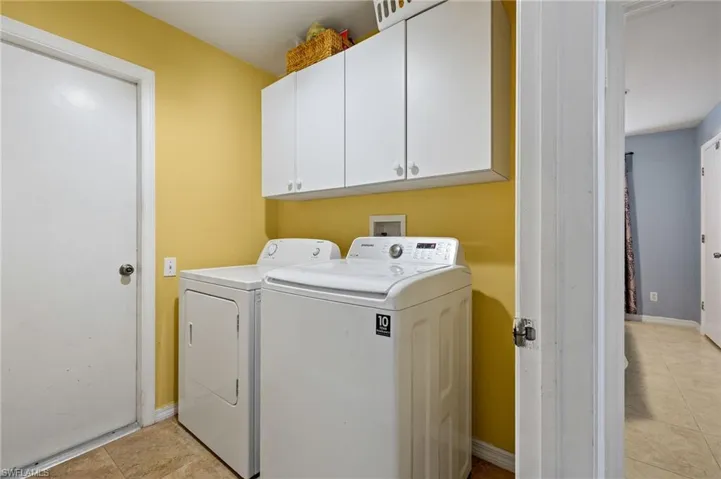 Laundry room with light tile patterned floors, baseboards, cabinet space, and washing machine and dryer