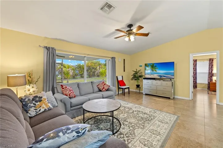 Tiled living room with visible vents, baseboards, ceiling fan, and vaulted ceiling
