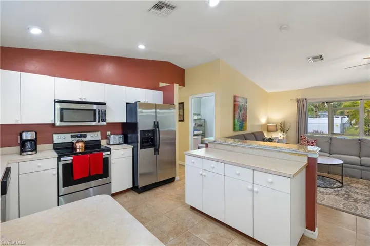 Kitchen with open floor plan, stainless steel appliances, light countertops, and visible vents