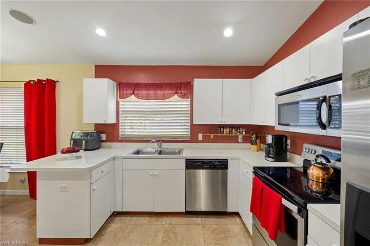 Kitchen with a peninsula, light countertops, appliances with stainless steel finishes, and a sink