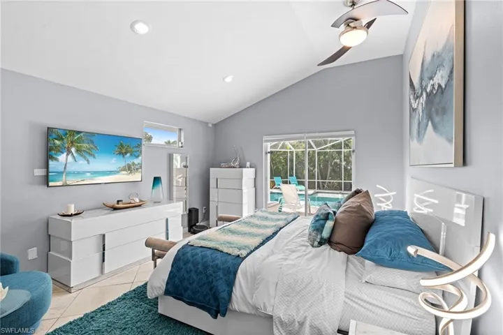 Tiled bedroom with ceiling fan, lofted ceiling, multiple windows, and access to outside