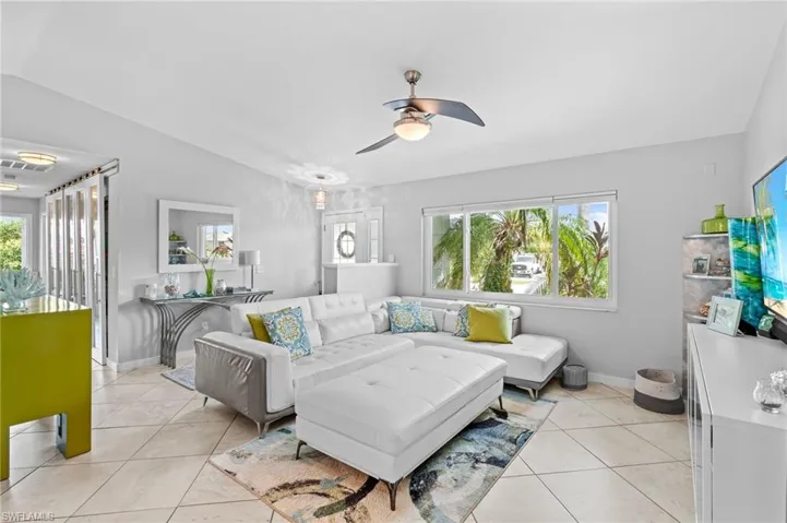 Tiled living room with vaulted ceiling, ceiling fan, and a healthy amount of sunlight