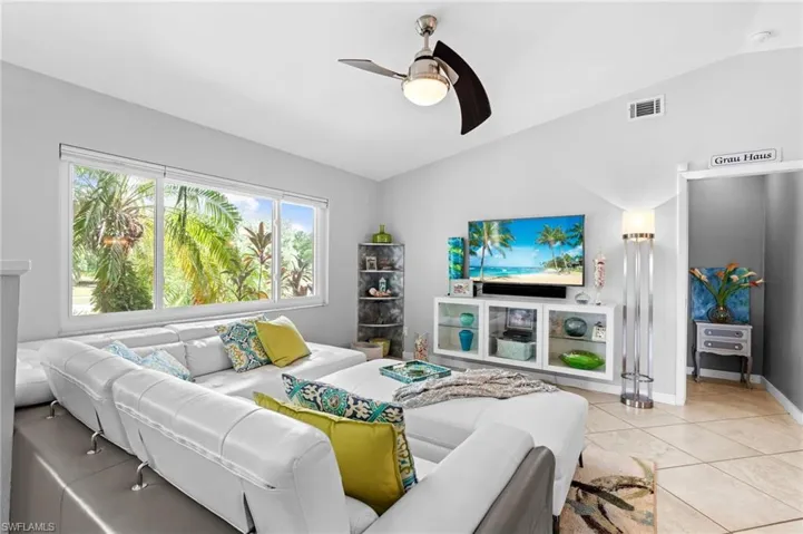 Living room with light tile patterned floors, vaulted ceiling, and ceiling fan