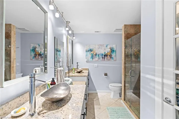 Bathroom with tile patterned floors, walk in shower, vanity, and toilet