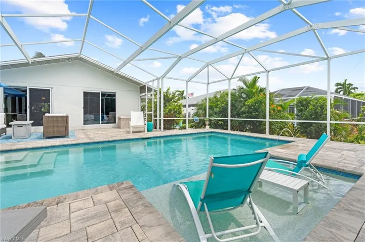 View of pool featuring glass enclosure and a patio