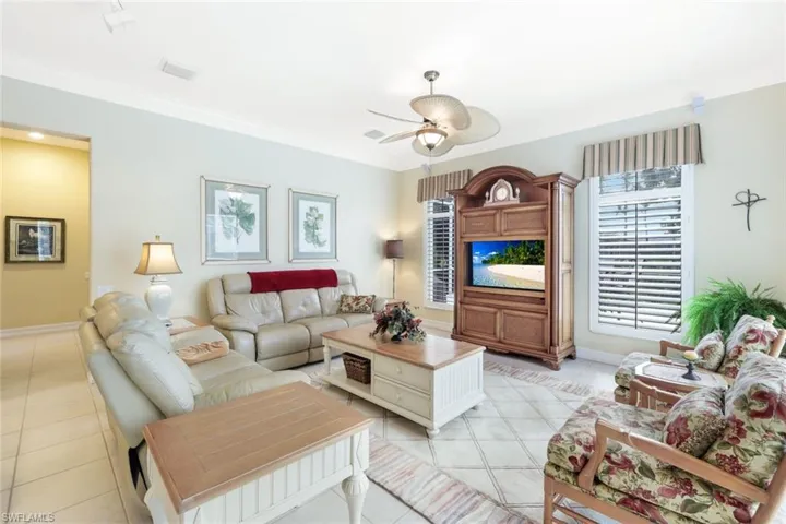 Tiled living room featuring crown molding and ceiling fan