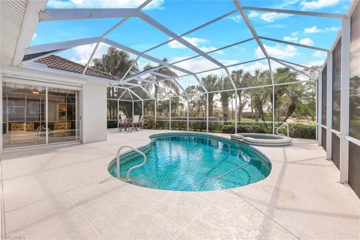 View of swimming pool with an in ground hot tub, a patio area, and glass enclosure