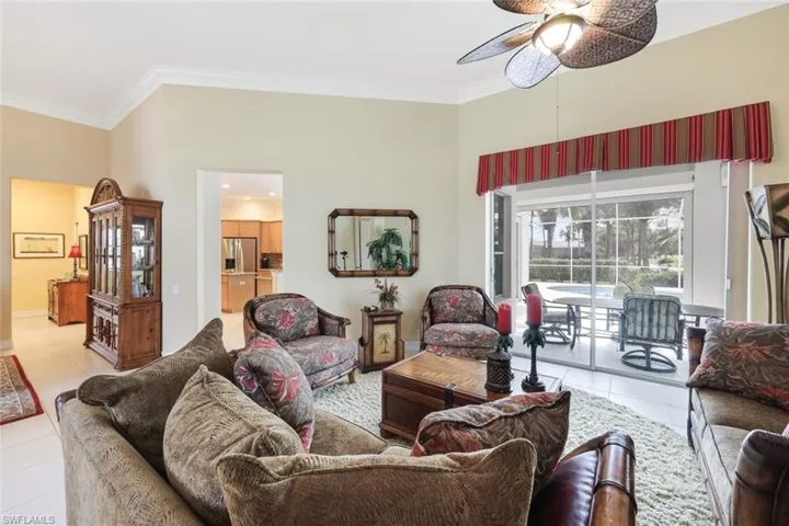 Living room featuring ornamental molding, ceiling fan, and light tile patterned floors