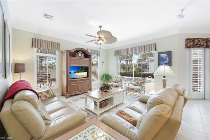 Living room with crown molding, a healthy amount of sunlight, light tile patterned floors, and ceiling fan