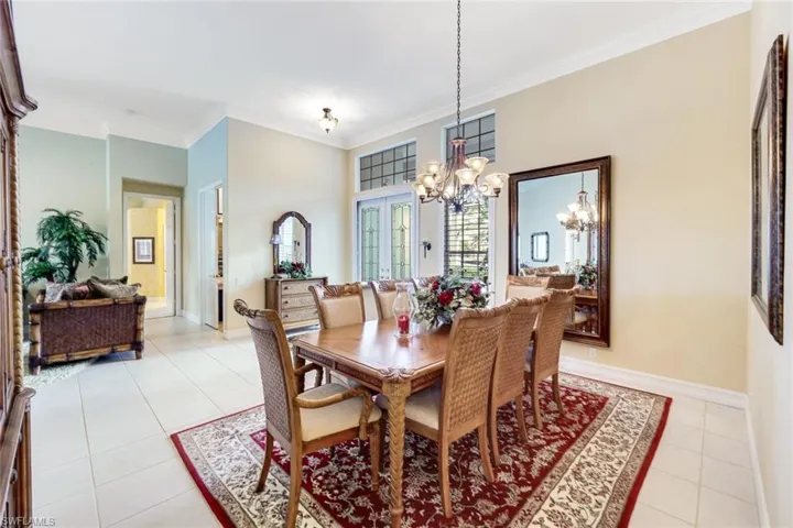 Dining room featuring french doors, crown molding, light tile patterned floors, and a chandelier