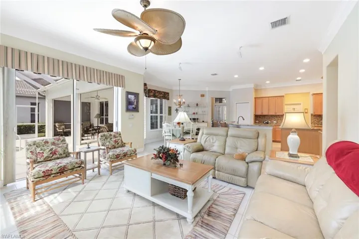Living room featuring crown molding and ceiling fan with notable chandelier