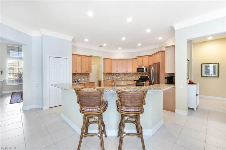 Kitchen with crown molding, stainless steel appliances, light stone countertops, and tasteful backsplash