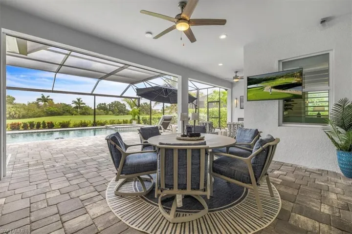 View of patio / terrace featuring a sunroom, a lanai, outdoor dining area, a ceiling fan, and a pool with connected hot tub