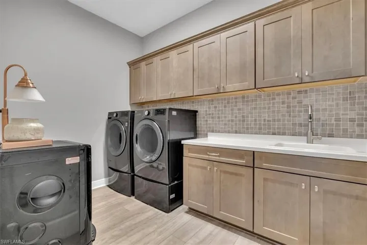 Laundry area with independent washer and dryer, cabinet space, and light wood-style flooring