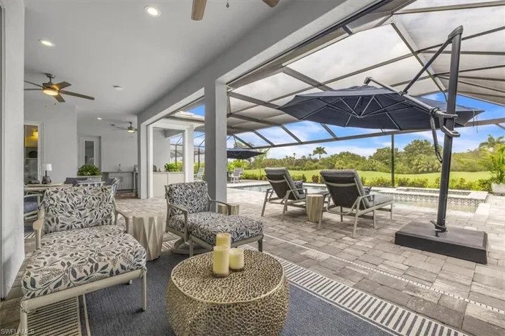 View of patio with a ceiling fan, a sunroom, glass enclosure, and an outdoor pool
