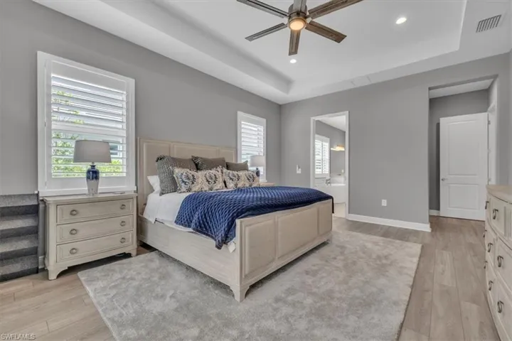 Primary Bedroom with a raised ceiling, light wood-style floors, ceiling fan, and recessed lighting