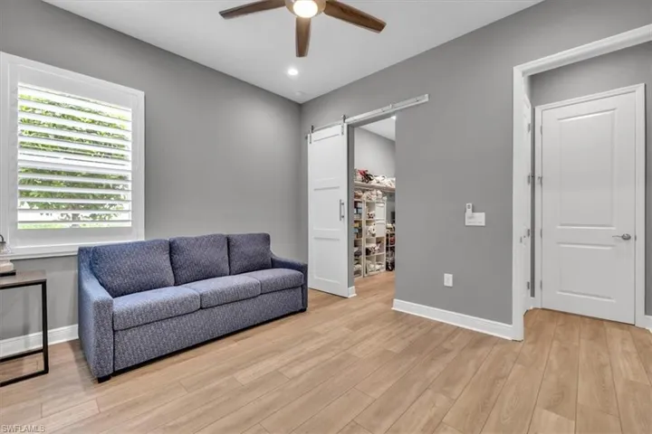 Living area featuring a barn door, light wood finished floors, ceiling fan, and recessed lighting