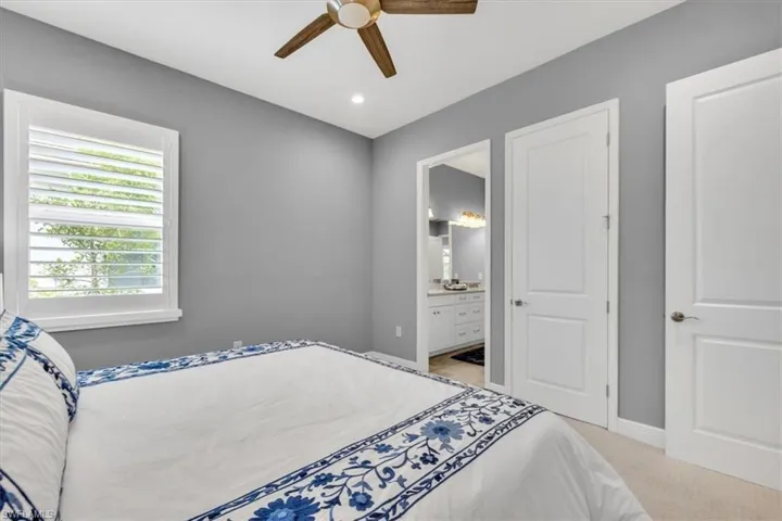 Bedroom with light colored carpet, a ceiling fan, ensuite bathroom, and recessed lighting