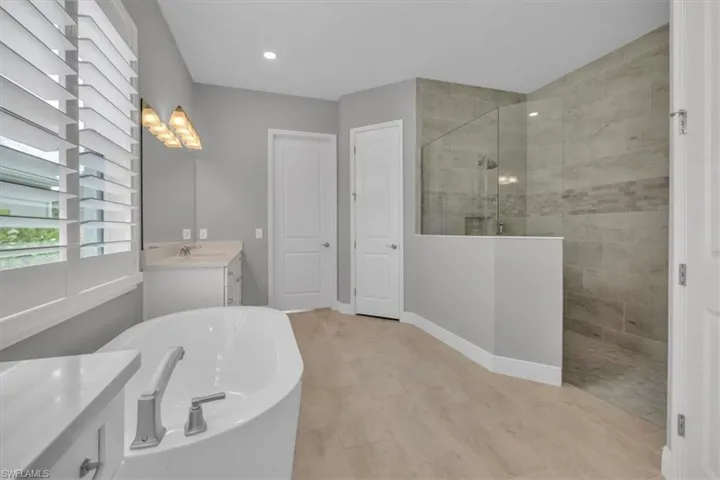 Primary Bathroom with vanity, a soaking tub, walk in shower, and recessed lighting