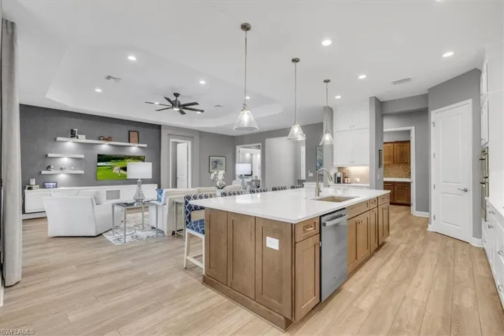 Kitchen with a kitchen breakfast bar, a tray ceiling, brown cabinets, white cabinetry, and decorative light fixtures