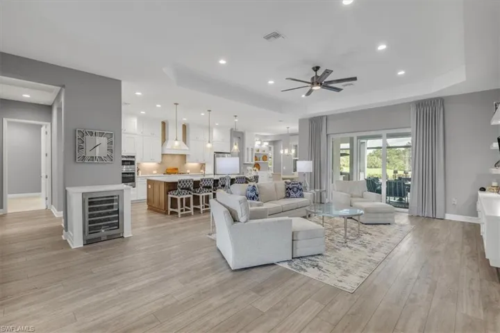 Living area with a raised ceiling, beverage cooler, recessed lighting, a ceiling fan