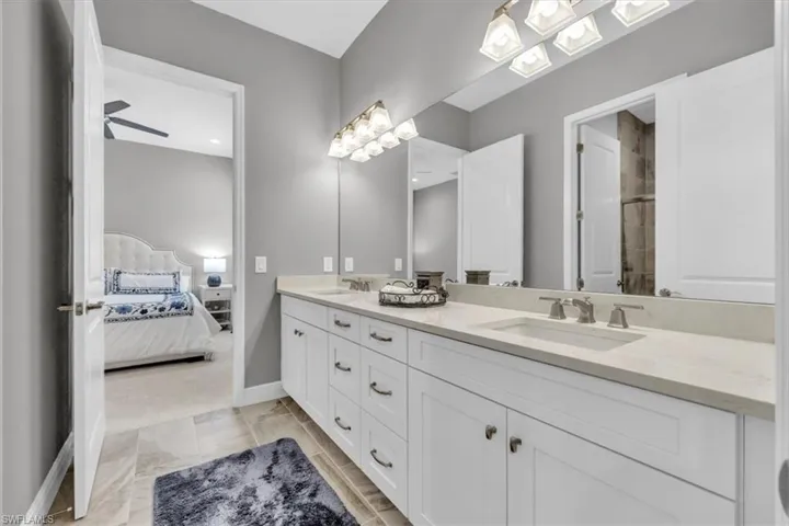 Bathroom with double vanity, connected bathroom, and a tile shower