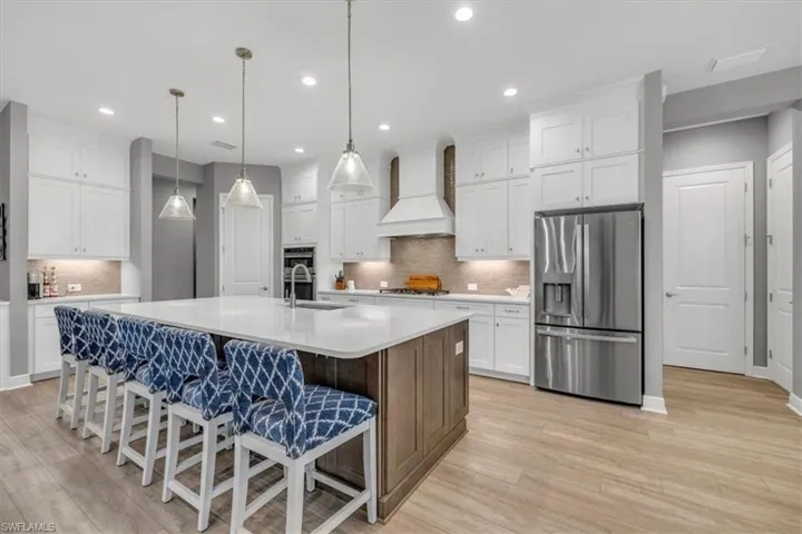 Kitchen with appliances with stainless steel finishes, white cabinets, a kitchen breakfast bar, a kitchen island with sink, and recessed lighting