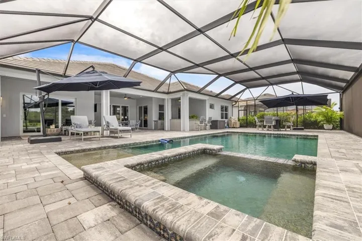 View of swimming pool featuring a sunroom, a ceiling fan, a pool with connected hot tub, a patio, and glass enclosure