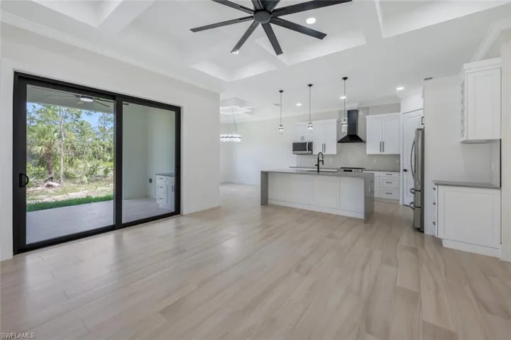 Kitchen with tasteful backsplash, wall chimney exhaust hood, coffered ceiling, stainless steel appliances, and ceiling fan