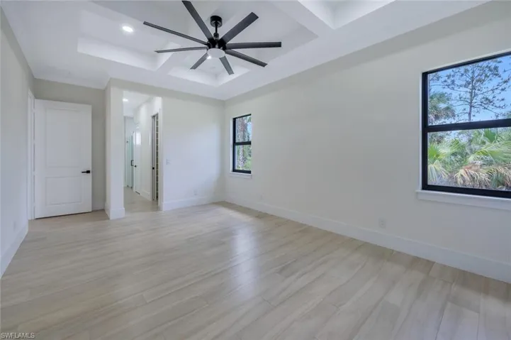 Spare room featuring baseboards, recessed lighting, light wood-style flooring, coffered ceiling, and ceiling fan