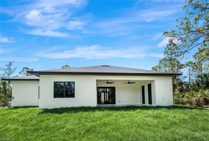 Back of property featuring a yard, ceiling fan, and stucco siding