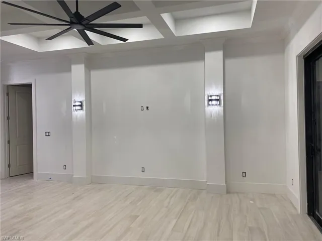 Empty room with baseboards, light wood-style floors, coffered ceiling, and crown molding