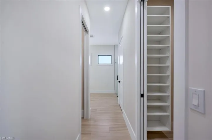 Hallway with light wood-style flooring, baseboards, and recessed lighting